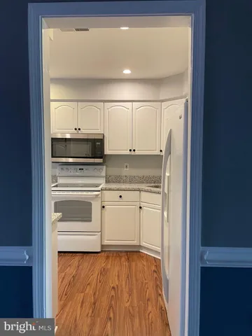 a kitchen with granite countertop white cabinets and white appliances