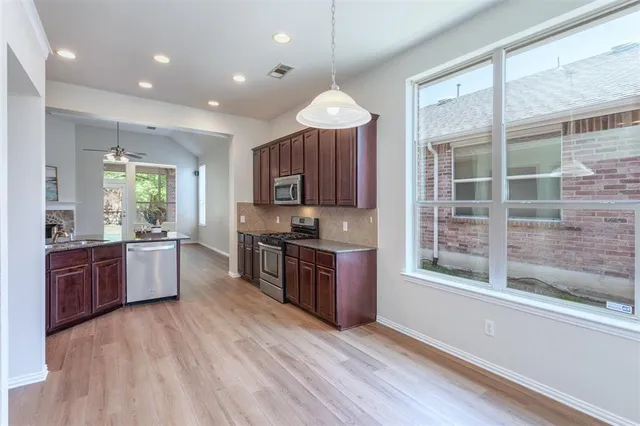 a large kitchen with kitchen island granite countertop a stove a sink dishwasher a microwave oven and a dining table with wooden floor