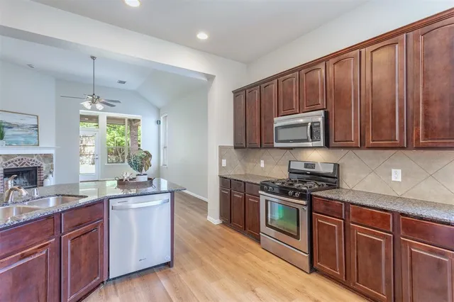 a kitchen with stainless steel appliances granite countertop wooden cabinets and a stove top oven