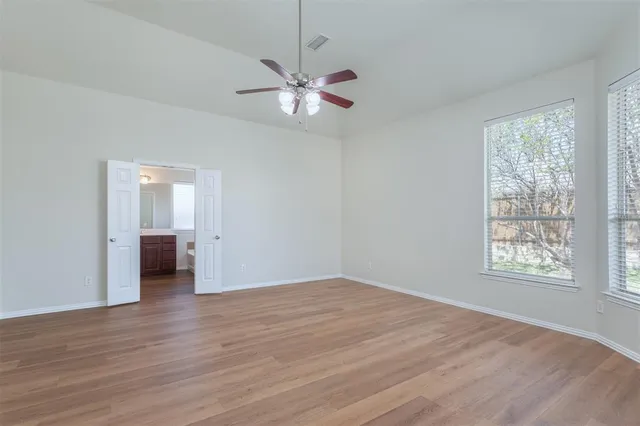 a view of empty room with wooden floor and fan