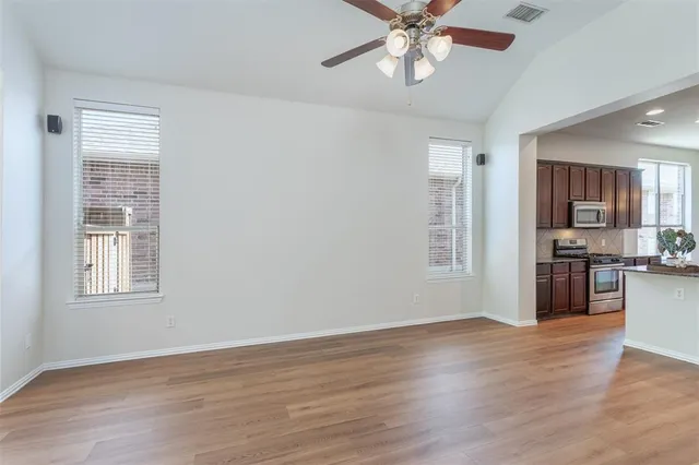 a view of an empty room with window and wooden floor