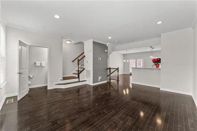 a view of an empty room with wooden floor and a kitchen