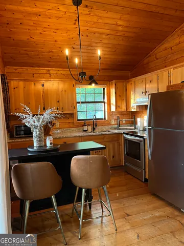 a kitchen with stainless steel appliances granite countertop a stove a sink refrigerator and a chair