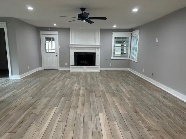 an empty room with wooden floor fireplace and windows