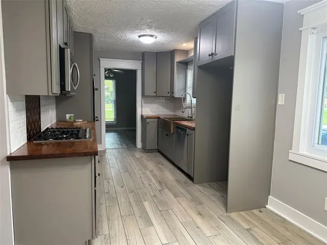 a kitchen with stainless steel appliances granite countertop a refrigerator a stove and a wooden floors