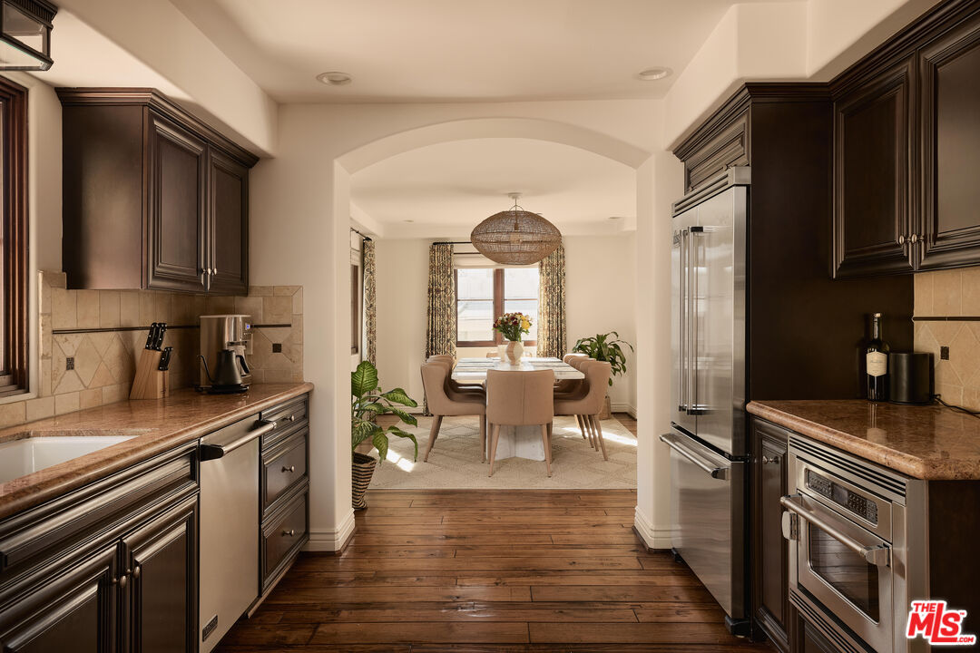 908 17th Street, Unit 8 Santa Monica, CA 90403 - Photo 7 of 15 a kitchen with stainless steel appliances granite countertop a stove top oven a sink dishwasher a dining table and chairs with wooden floor