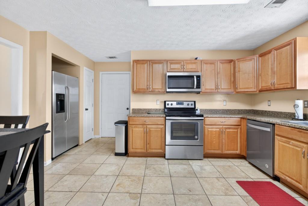 701 Muirfield Drive Winder, GA 30680 - Photo 15 of 35 a kitchen with stainless steel appliances granite countertop a stove top oven a sink dishwasher and a refrigerator