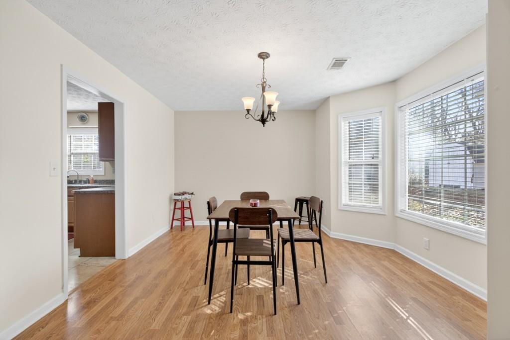 701 Muirfield Drive Winder, GA 30680 - Photo 10 of 35 a dining room with wooden floor a chandelier a wooden table and chairs