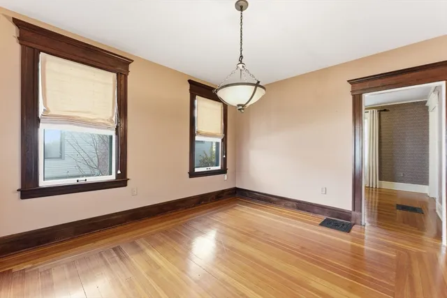a view of an empty room with a window and wooden floor
