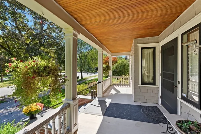 a porch with chairs next to a yard
