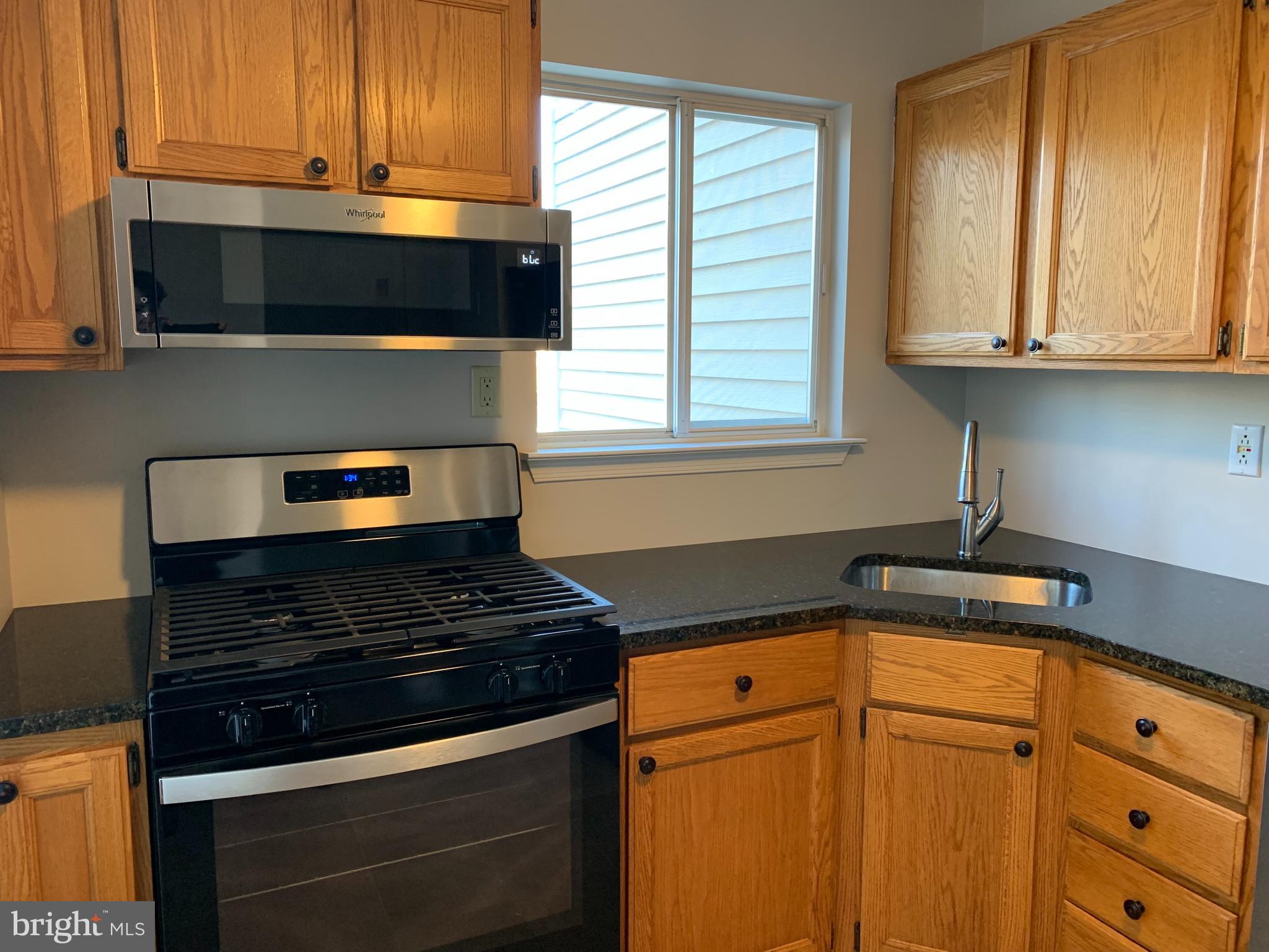 335 Silvia Street Ewing, NJ 08628 - Photo 5 of 25 a kitchen with granite countertop white cabinets and black appliances