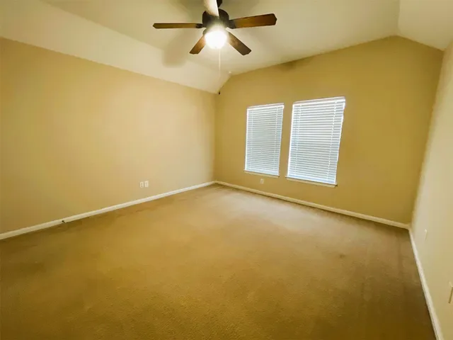 an empty room with a ceiling fan and window