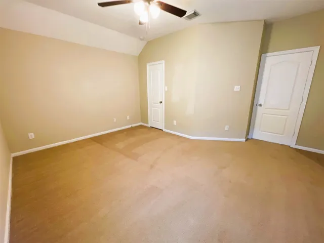 an empty room with a ceiling fan and wooden floor