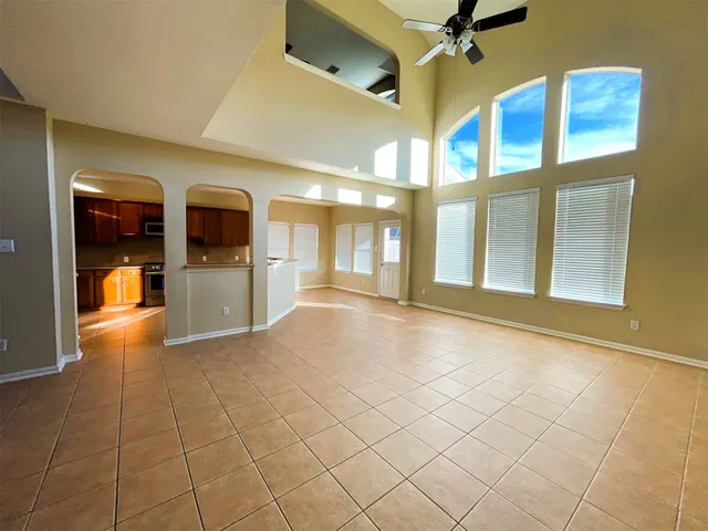 a view of an empty room with a window and kitchen view