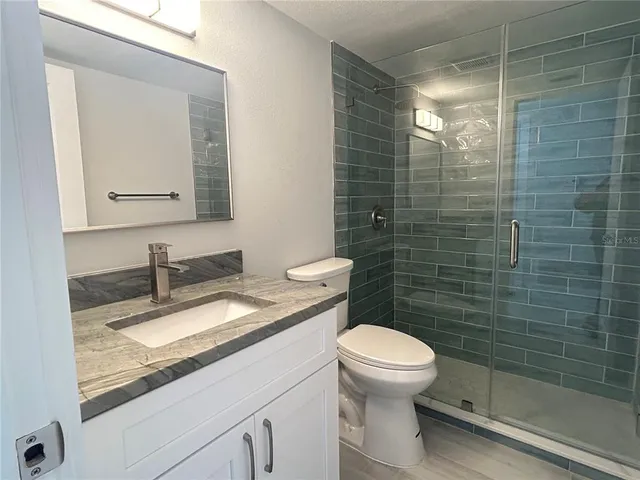 a bathroom with a granite countertop toilet sink and mirror