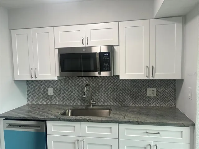 a kitchen with stainless steel appliances granite countertop white cabinets a sink and dishwasher