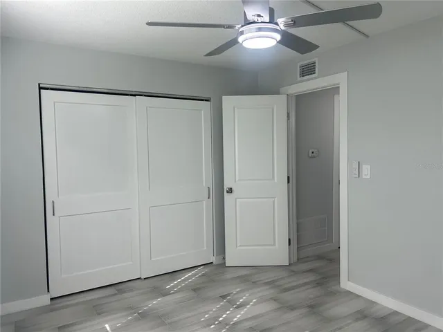 an empty room with closet and a ceiling fan