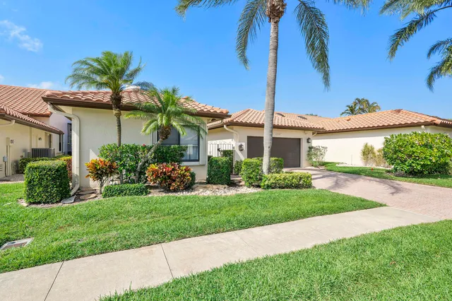a front view of a house with a garden and trees