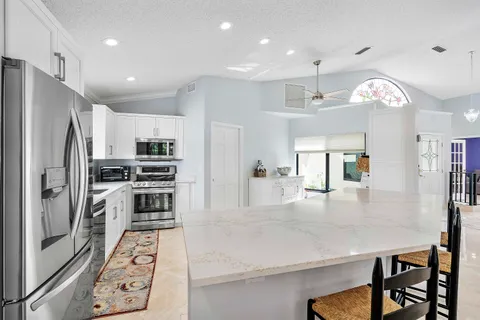 a kitchen with stainless steel appliances kitchen island granite countertop a refrigerator a stove and a sink with large countertops