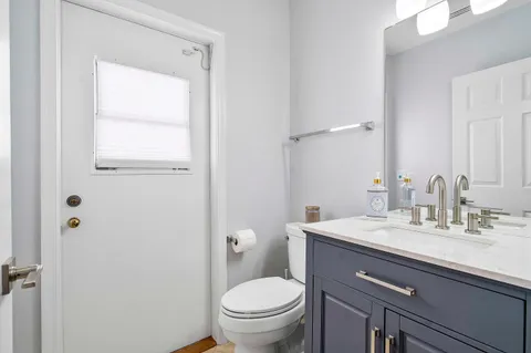 a bathroom with a granite countertop sink toilet and mirror