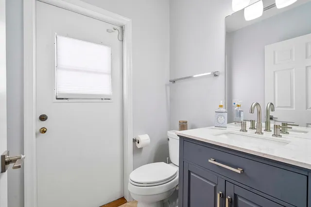 a bathroom with a granite countertop sink toilet and mirror