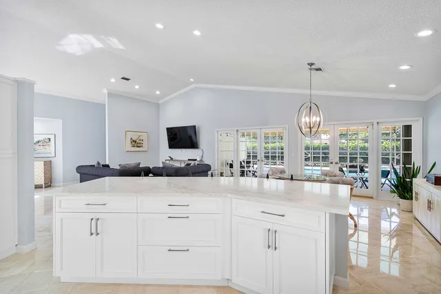 a large kitchen with kitchen island a chandelier and living room view