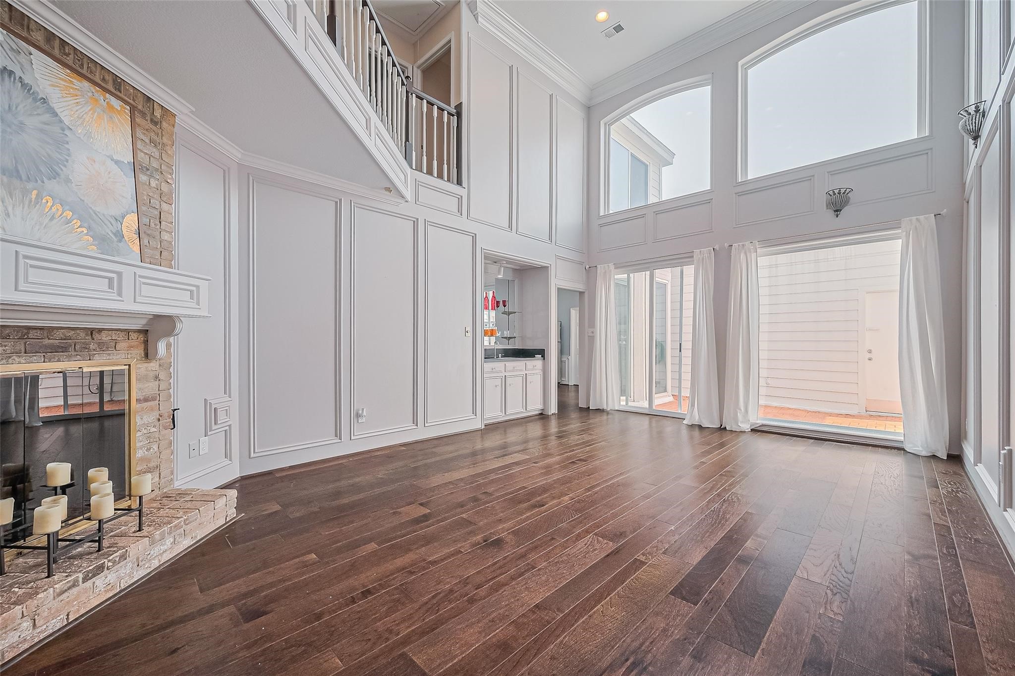 4305 Westheimer Road Houston, TX 77027 - Photo 5 of 25 Expansive living room with soaring ceilings, abundant natural light from large windows, elegant wood flooring, and a cozy fireplace for a perfect blend of style and comfort.