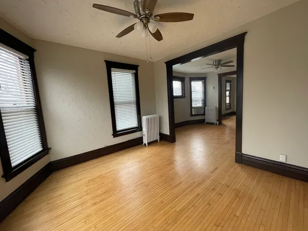 a view of an empty room with wooden floor and a window