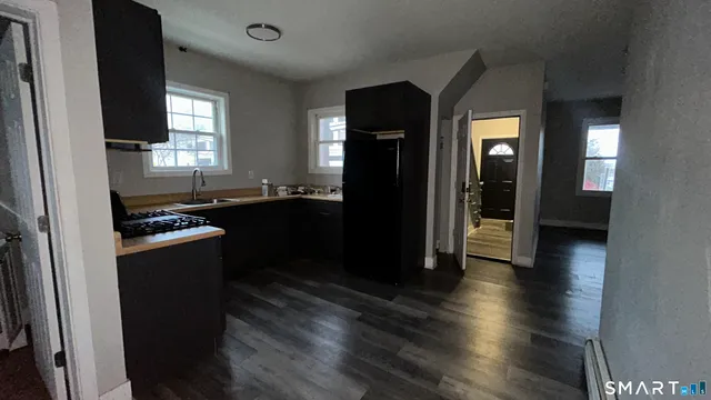 a kitchen with stainless steel appliances granite countertop a refrigerator a sink dishwasher a stove and white countertops with wooden floor