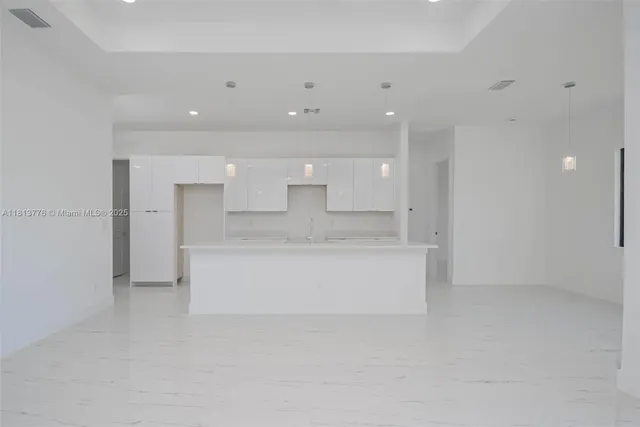 a large white kitchen with a refrigerator a sink dishwasher with a dining table and chairs