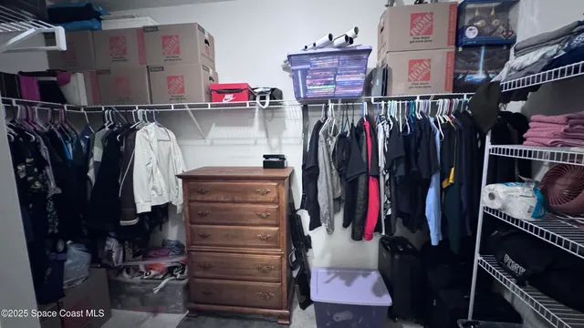 a view of walk in closet with clothes and shoes