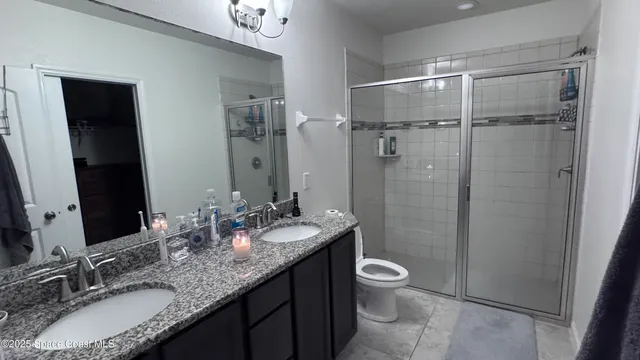 a bathroom with a granite countertop sink toilet a large mirror a shower and a mirror