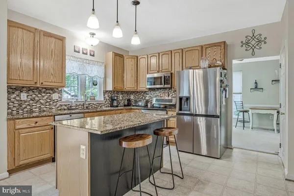 a kitchen with granite countertop a stove a sink a dining table and chairs