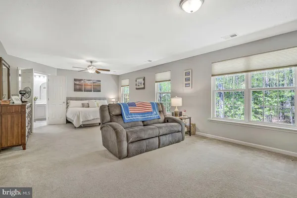 a spacious bedroom with a bed a dresser and a mirror