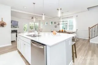a kitchen with stainless steel appliances kitchen island a table chairs in it and wooden floors