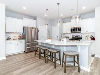 a kitchen with a refrigerator a stove a sink and white cabinets with wooden floor