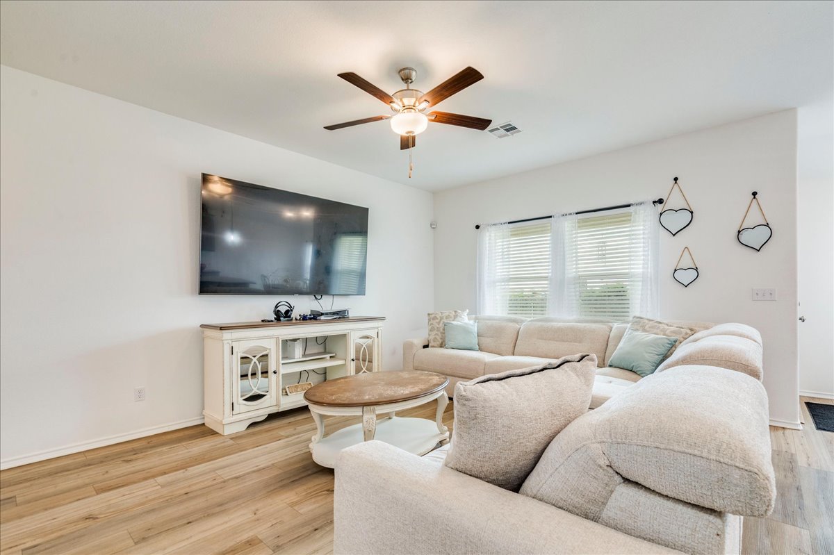 389 Salt Springs Road Kyle, TX 78640 - Photo 8 of 30 A well-lit living space features bright flooring and a ceiling fan, creating an inviting atmosphere.