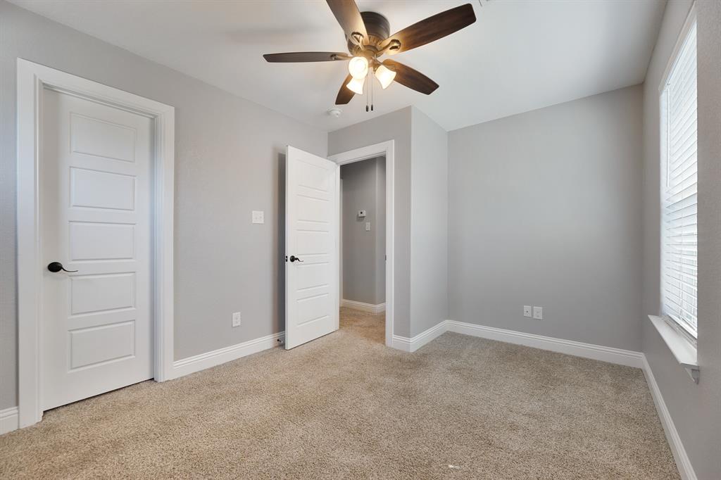 1713 Bronco Road Granbury, TX 76049 - Photo 22 of 23 Carpeted room with light gray walls, white baseboards, and a ceiling fan with integrated lighting