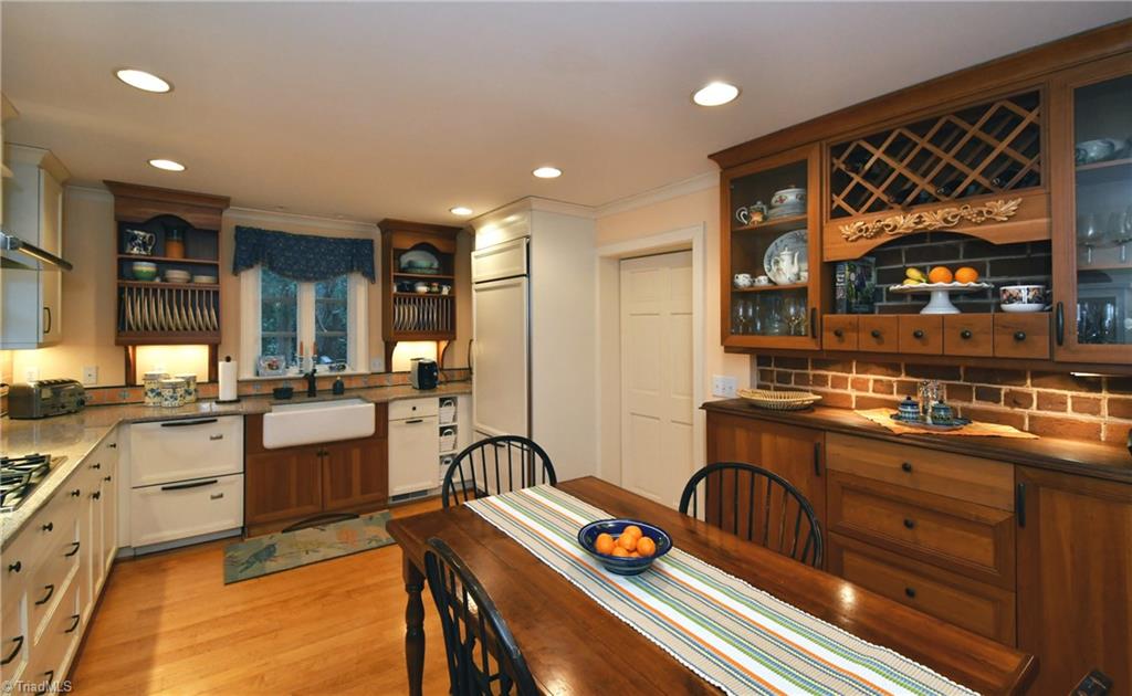 3250 Beroth Road Pfafftown, NC 27040 - Photo 22 of 30 To note a few of the kitchens details: farm sink, plate rack, two drawer dishwasher, gas cooktop, wall ovens, builtin refrigerator, and furniture-quality buffet with wine rack, wine cooler, glass front cabinets, and walnut countertop. The maple floors here beautifully match those original to the house.