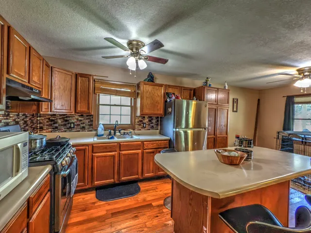a kitchen with stainless steel appliances a sink a stove a refrigerator cabinets and wooden floor