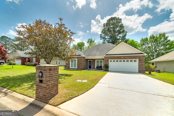 a front view of house with yard and trees in the background