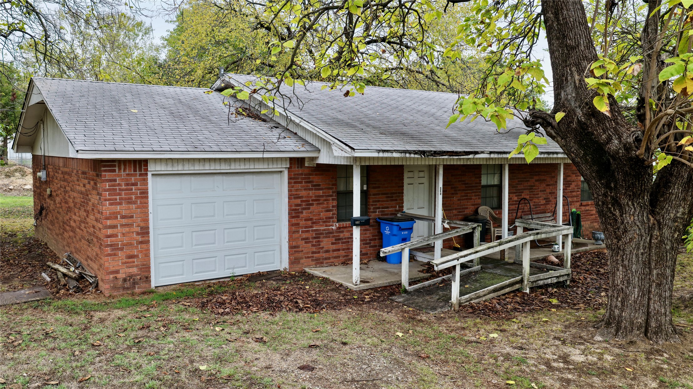 602 Northwest 4th Street Checotah, OK 74426 - Photo 3 of 28 Brick exterior with an attached garage, covered front porch, and an accessibility ramp