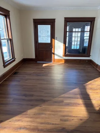 a view of an empty room with wooden floor and a window