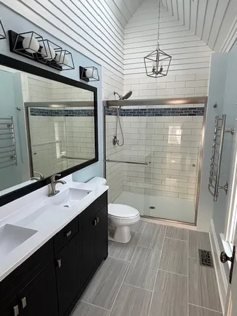 a bathroom with a sink a toilet a mirror and shower