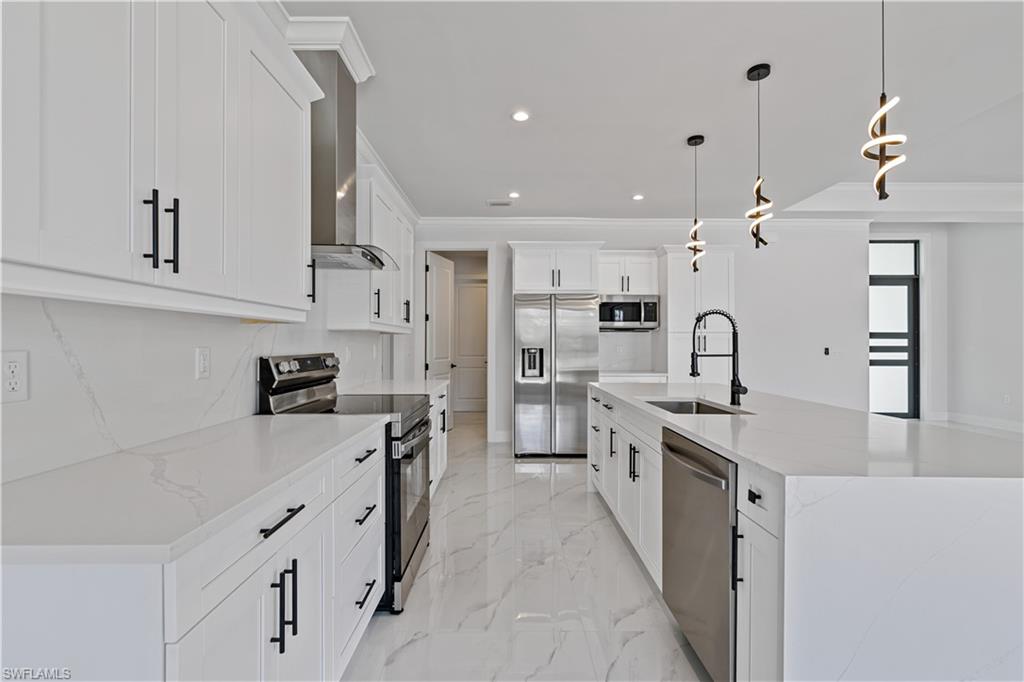 3397 14th Avenue Southeast Naples, FL 34117 - Photo 15 of 28 a large kitchen with stainless steel appliances kitchen island granite countertop a refrigerator a stove a sink dishwasher and white cabinets with wooden floor