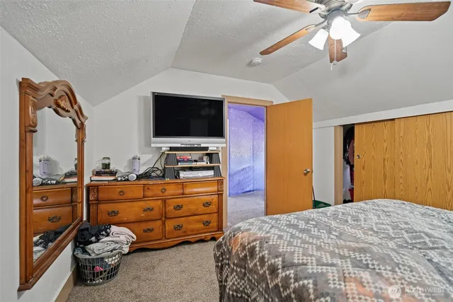 a bedroom with a bed and a flat tv screen on dresser