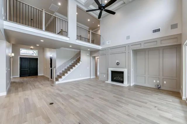 a view of a livingroom with a fireplace a ceiling fan and windows