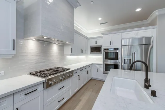 a kitchen with a stove a sink a center island and wooden floor