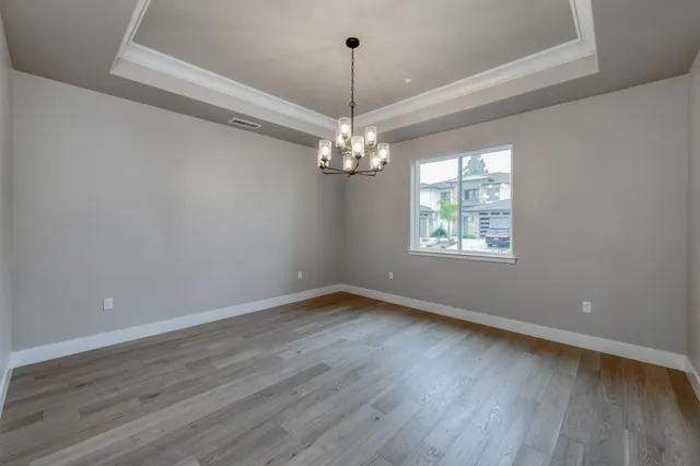 a view of a hallway with wooden floor and a chandelier