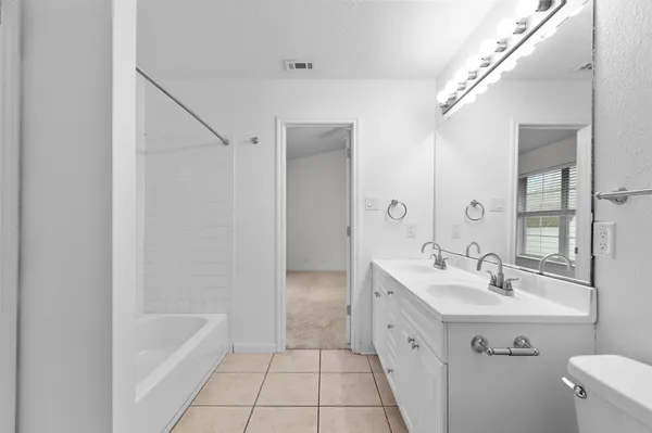 a bathroom with a double vanity sink a mirror and a bathtub